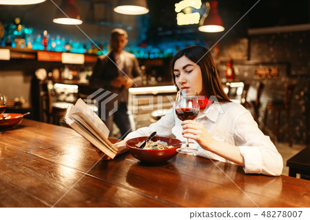 Woman reading a book at wooden bar counter Woman reading a book at wooden bar counter 48278007