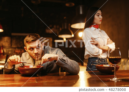 Couple in quarrel, man eats at bar counter Couple in quarrel, man eats at bar counter 48278008