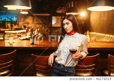 Woman with glass of red wine at wooden bar counter 48278014
