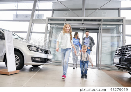 Happy family with children entering dealership showroom. 48279059