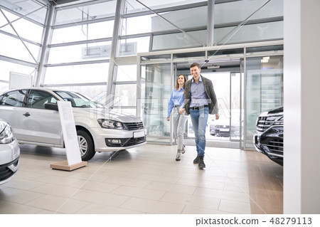 Couple entering dealership showroom, holding hands. Couple entering dealership showroom, holding hands. 48279113