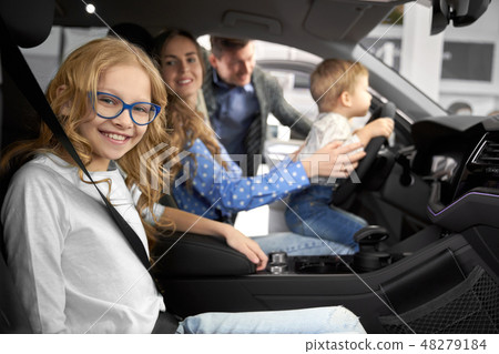 Family posing in car cabin of new automobile. 48279184