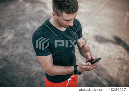 Male athlete, summer on sports field in his hand smartphone writes message to Internet, application 48280017