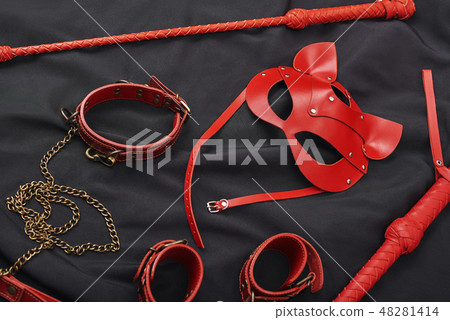 BDSM leather kit. Top view of red bdsm leather set: handcuffs, whip, mask 48281414