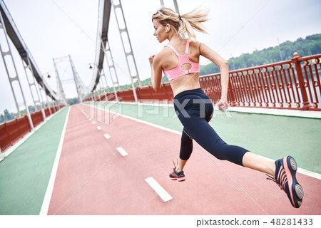 Morning workout. Full length rear view of young womanin sports clothing exercising while jogging on 48281433