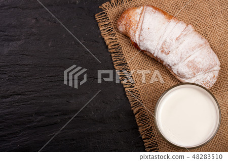 glass of milk with croissants on black stone background with copy space for your text. Top view glass of milk with croissants on black stone background with copy space for your text. Top view 48283510