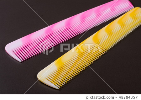 Two different colored hairbrushes on a dark background Two different colored hairbrushes on a dark background 48284357
