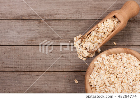 Oat flakes in a wooden bowl with a scoop on old wooden background with copy space for your text. Top 48284774