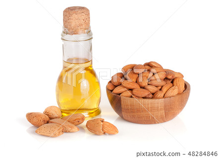 Bottle of almond oil and almonds in a wooden bowl isolated on white background Bottle of almond oil and almonds in a wooden bowl isolated on white background 48284846