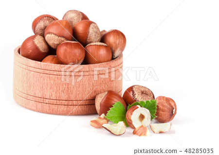 Hazelnuts with leaves in a wooden bowl isolated on white background Hazelnuts with leaves in a wooden bowl isolated on white background 48285035