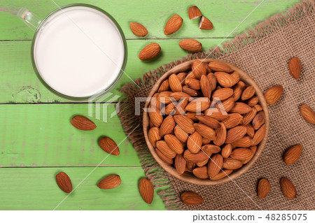 Almond milk in a glass and almonds in a bowl on green wooden background. Top view Almond milk in a glass and almonds in a bowl on green wooden background. Top view 48285075