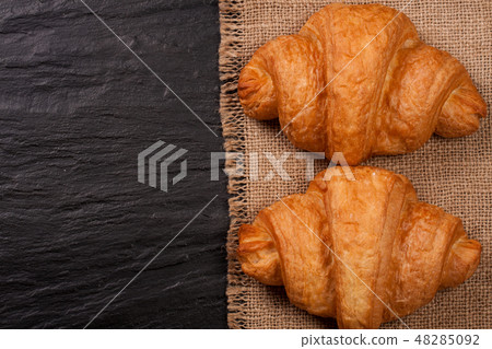 two croissant on black stone background with copy space for your text. Top view two croissant on black stone background with copy space for your text. Top view 48285092