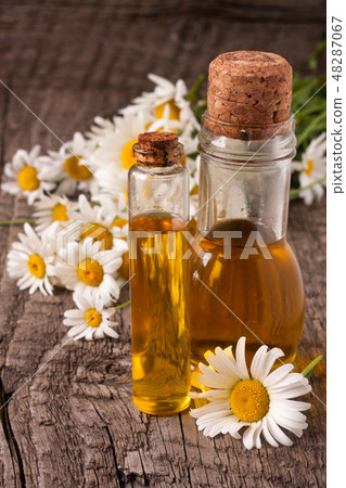 bottle with essential oil and fresh chamomile flowers on a old wooden background 48287067