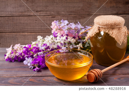 Jar of honey with wildflowers on a dark wooden background Jar of honey with wildflowers on a dark wooden background 48288916