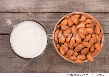 Almond milk in a glass and almonds in a bowl on old wooden background. Top view 48289579