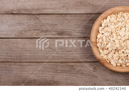 Oat flakes in a wooden bowl on old wooden background with copy space for your text. Top view 48292140