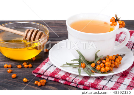 Tea of sea-buckthorn berries with honey on wooden table isolated white background Tea of sea-buckthorn berries with honey on wooden table isolated white background 48292320