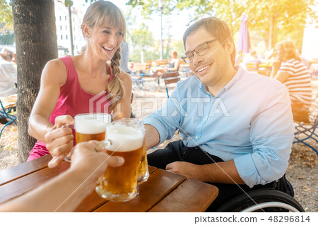 Friends in beer garden drinking, one man is in a wheelchair Friends in beer garden drinking, one man is in a wheelchair 48296814