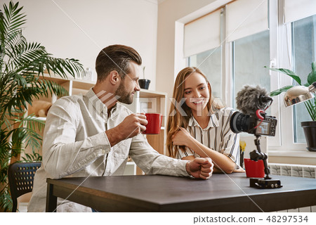 Successful bloggers. Smiling bloggers drinking a tea while making new content for their blog 48297534
