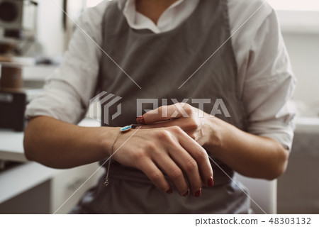Perfect present. Portrait of female jeweler wearing silver bracelet while working at her jewellery 48303132