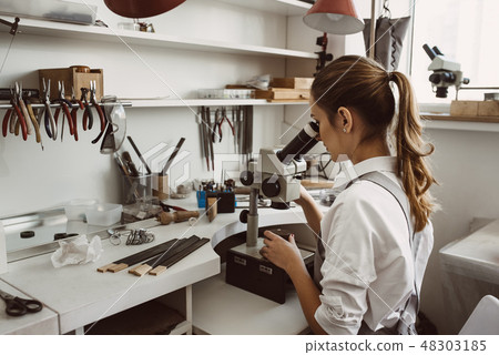 She knows what she is doing. Portrait of female jeweler looking at the new jewelery product through 48303185