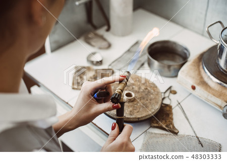 Working with a fire. Female jeweler's hands soldering and welding silver ring at her jewelry making 48303333