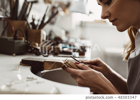 I got my inspiration. Side view of a female excited jeweler creating a silver ring at her workbench 48303347