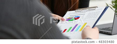 Female arm holding silver pen point in financial graph 48303480