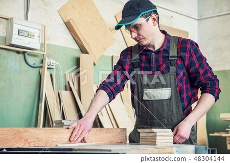 Construction worker cutting wooden board 48304144