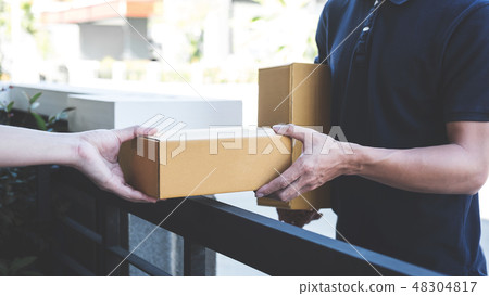 Delivery mail man giving parcel box to recipient, Young owner ac Delivery mail man giving parcel box to recipient, Young owner ac 48304817