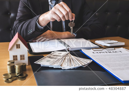 Estate agent giving house keys to client after signing agreement 48304887