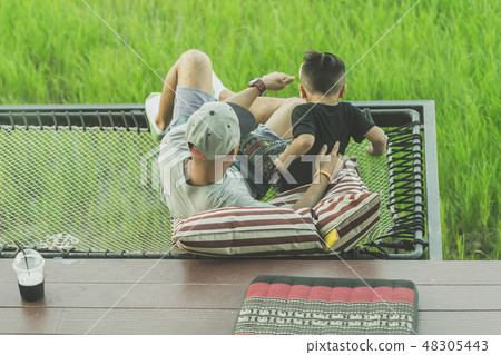 Dad and son relax on the balcony Dad and son relax on the balcony 48305443