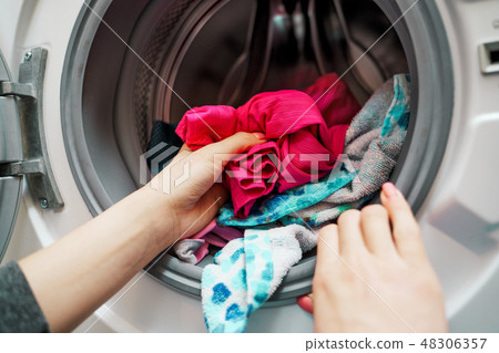 Image of female hands putting dirty clothes in washing machine 48306357