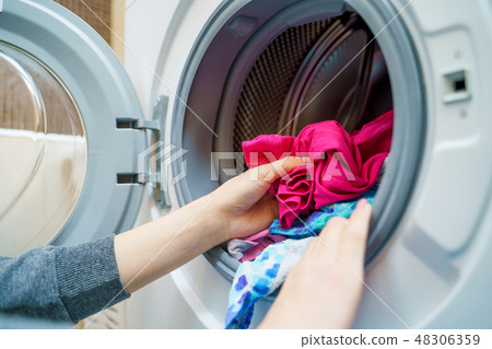 Female hands putting dirty clothes in washing machine 48306359