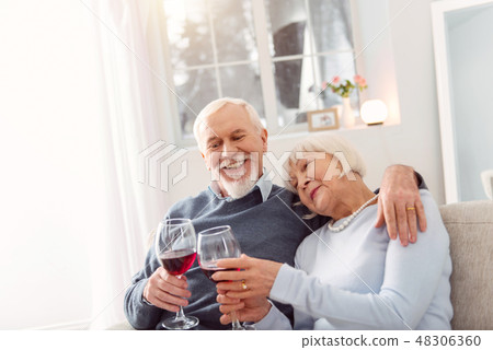 Happy senior couple cuddling while drinking wife Happy senior couple cuddling while drinking wife 48306360