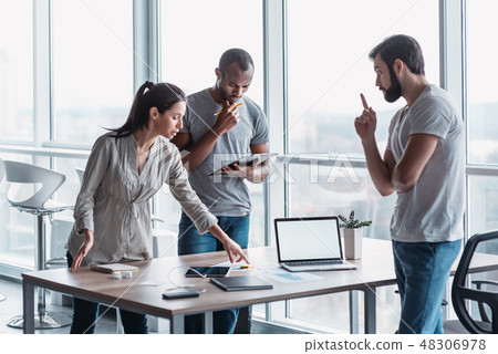Diverse group of focused colleagues discussing business strategy together during a meeting in an 48306978