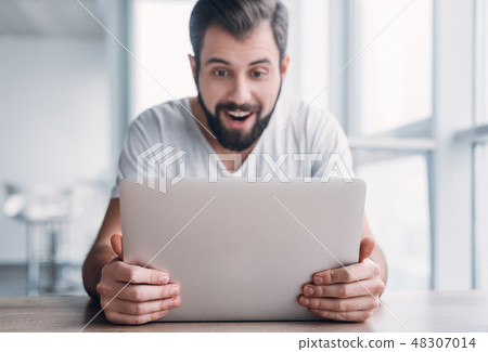 Portrait of shocked young man working on laptop computer and looking surprised on the screen Portrait of shocked young man working on laptop computer and looking surprised on the screen 48307014