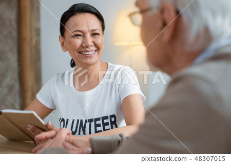 Cheerful volunteer communicating with senior man Cheerful volunteer communicating with senior man 48307015