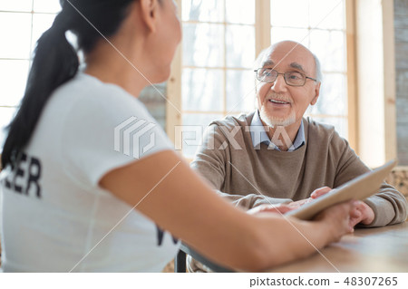 Volunteer and senior man discoursing over book Volunteer and senior man discoursing over book 48307265