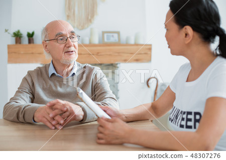 Volunteer and focused senior man debating over book Volunteer and focused senior man debating over book 48307276