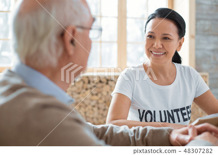 Pleasant volunteer and senior man discussing book Pleasant volunteer and senior man discussing book 48307282