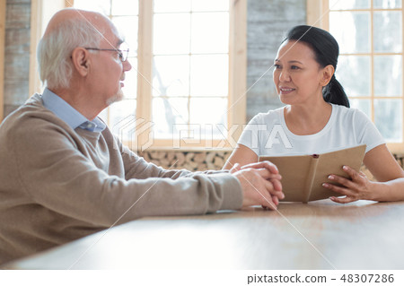 Positive volunteer reading to senior man 48307286