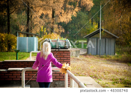 Young blonde woman in violet coat in park Young blonde woman in violet coat in park 48308748