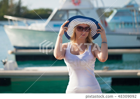 Young blonde with hat near yachts at the pier Young blonde with hat near yachts at the pier 48309092