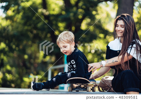 Beautiful young hipster mom and little son at the skatepark Beautiful young hipster mom and little son at the skatepark 48309581
