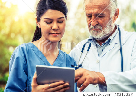 Senior and young doctor working in the park. Senior and young doctor working in the park. 48313357