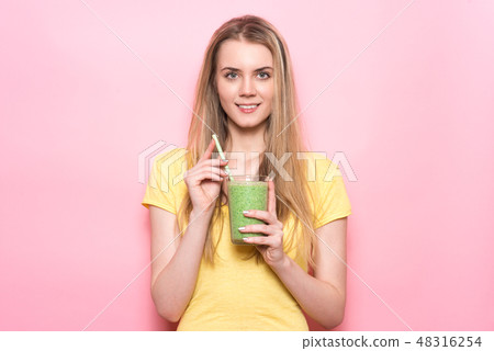 Cute young woman drinking a green smoothie 48316254