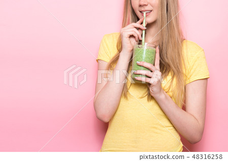 Cute young woman drinking a green smoothie 48316258