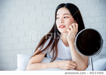 Asian teenage woman looking at mirror and acne 48317009