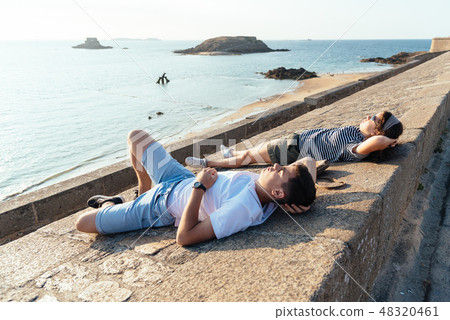 Portrait of young couple relaxing lying on the walls Portrait of young couple relaxing lying on the walls 48320461